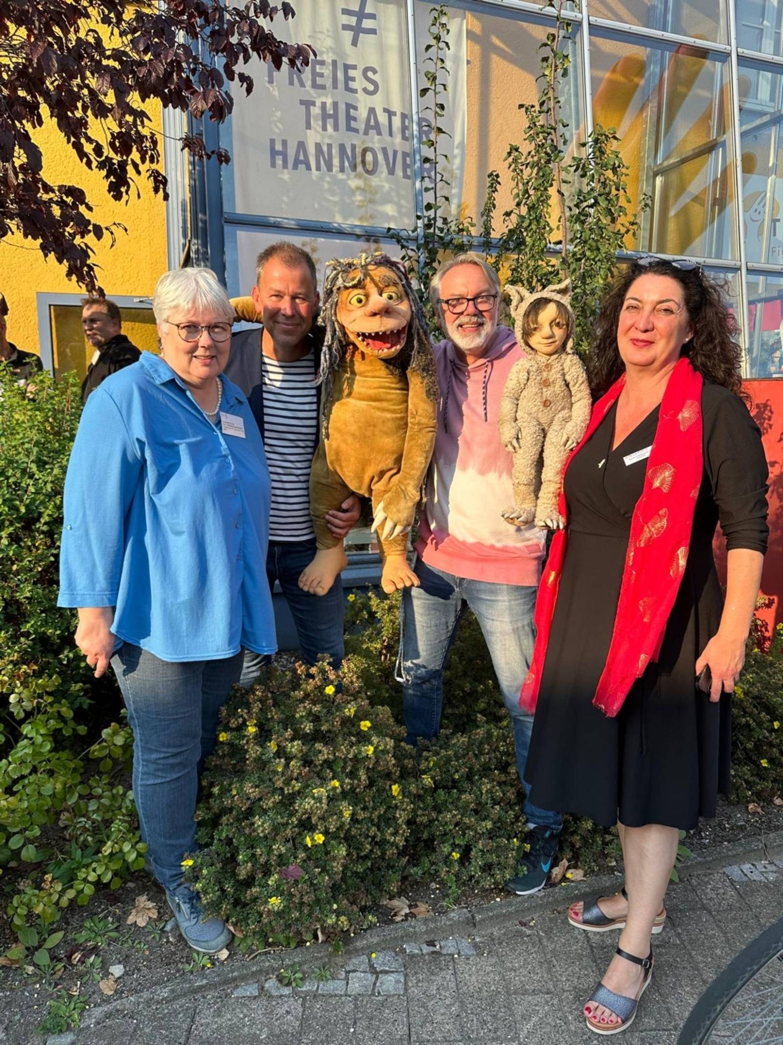 Es sind vier Personen auf dem Bild zu sehen mit zwei Theaterfiguren aus dem Theatrio Hannover