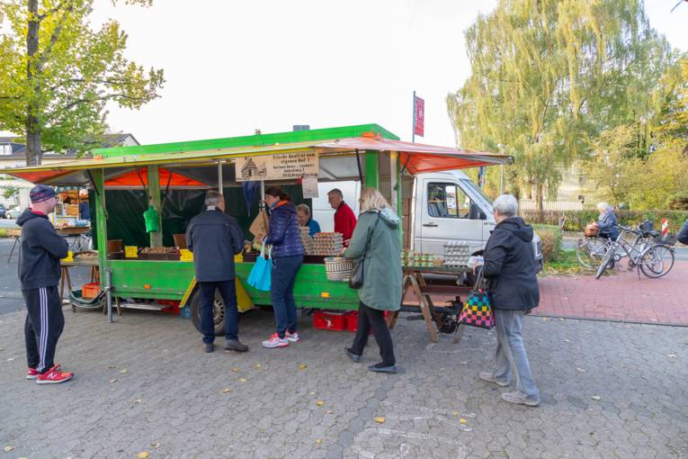 Menschen stehen an einem Marktwagen auf dem Wochenmarkt Misburg.