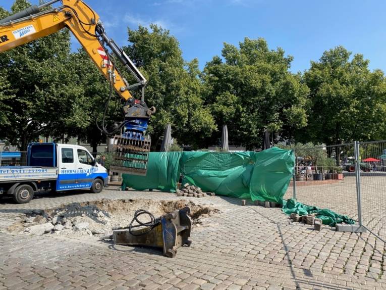 Eine Baustelle mit einem Kran und einer grünen Plane.