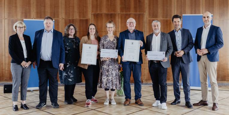 Eine Gruppe von Personen, von denen einige eine Urkunde in der Hand halten