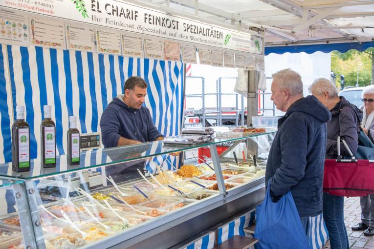 Menschen stehen Schlange an einem Feinkost-Marktstand