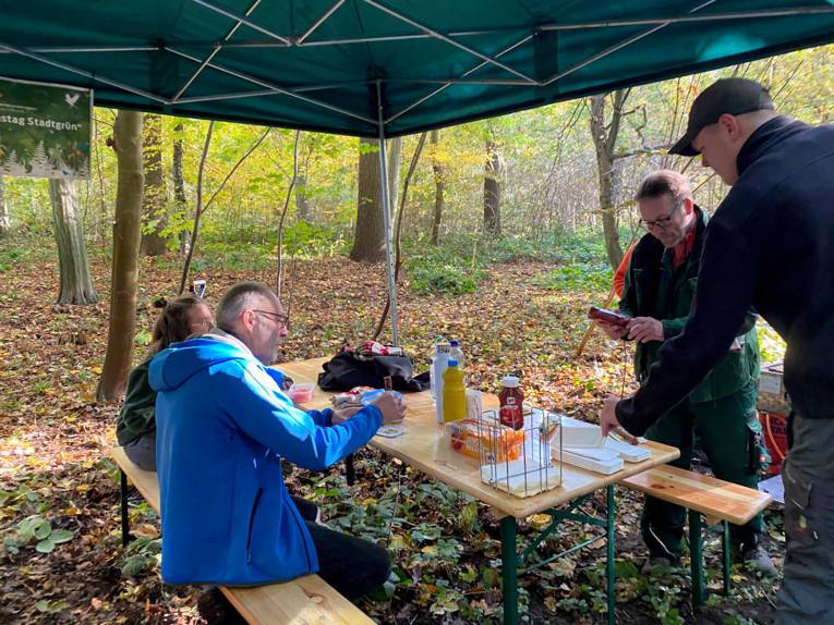 Menschen, die sich im Wald mit Gegrilltem stärken.