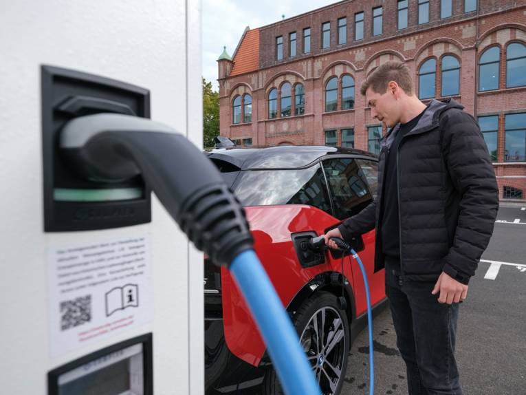 Mann lädt ein E-Auto an E-Ladesäule