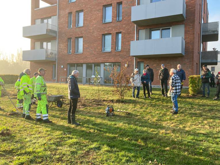 Menschen auf einer Grünfläche vor einem Haus.